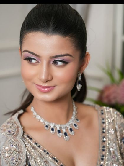 A close-up of a model wearing a diamond and sapphire necklace that perfectly matches her silver and blue lehenga.