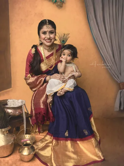 A classic pose with mother and child. The rich colors of the saree and the warm, painterly background create a portrait that feels both regal and intimate.