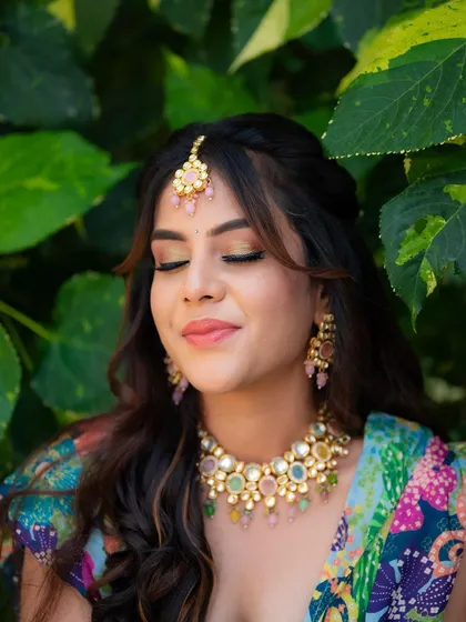 A close-up of the model's makeup and jewelry for her Mehendi look. The soft focus and her peaceful expression highlight the artistry of the makeup artist.