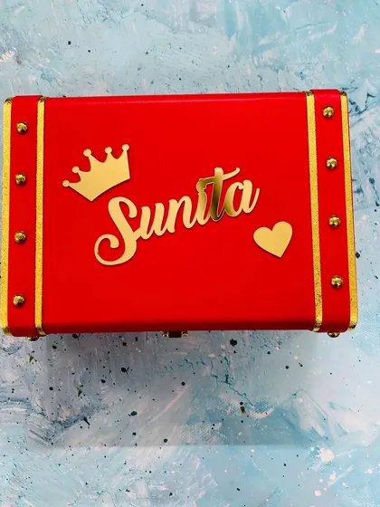 This vibrant red trunk box is personalized with the name "Sunita" and a heart charm, making it a bold and loving gift.