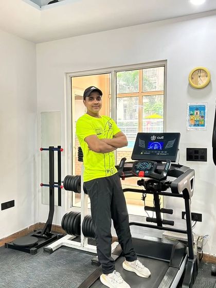 Standing by the treadmill in a bright shirt, feeling energized. A positive mindset is a big part of having a successful workout.