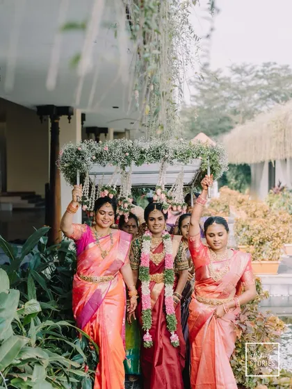 The bride's grand entrance, escorted by her family under a beautiful floral canopy. This image captures the tradition and support surrounding the bride.