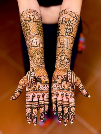A beautiful example of incorporating initials ("GT") into a traditional design. The mehndi is filled with classic elements like peacocks, elephants, and lotus flowers.
