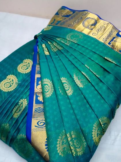 A beautiful teal saree with a blue and gold border, pleated and folded. Just send in your sarees and I'll take care of the rest.
