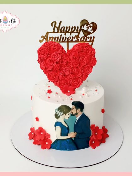A romantic anniversary cake featuring a hand-painted portrait of the couple. The design is topped with a heart made of red roses, symbolizing their love.