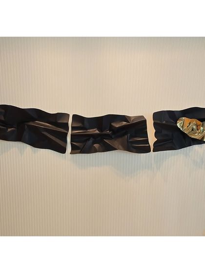 The full three-panel black and gold sculpture, stretching across the wall to create a dramatic, panoramic artwork.