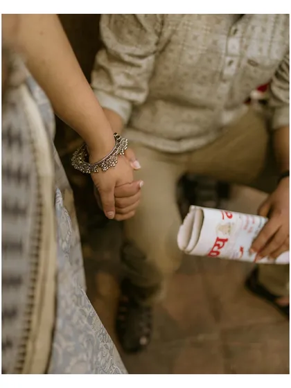 A detailed shot of a couple holding hands, with a rolled-up newspaper as a prop. This close-up highlights the simple, meaningful gestures of an old-school romance.