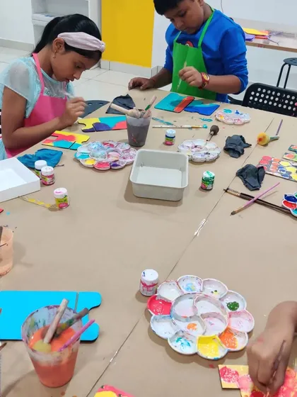 A busy table at an art party where kids are painting and creating their own personalized desk calendars.