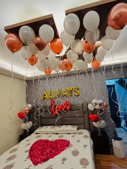 A close-up of the 'Always Love' anniversary decor, highlighting the mix of white and metallic balloons and the rose petal heart.