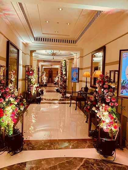 An elegant hallway decorated with tall floral arrangements, leading guests towards the main celebration area in style.