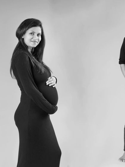 A simple and elegant black and white portrait focusing on the mother-to-be. Her partner is softly blurred in the background, symbolizing his supportive presence on this beautiful journey.