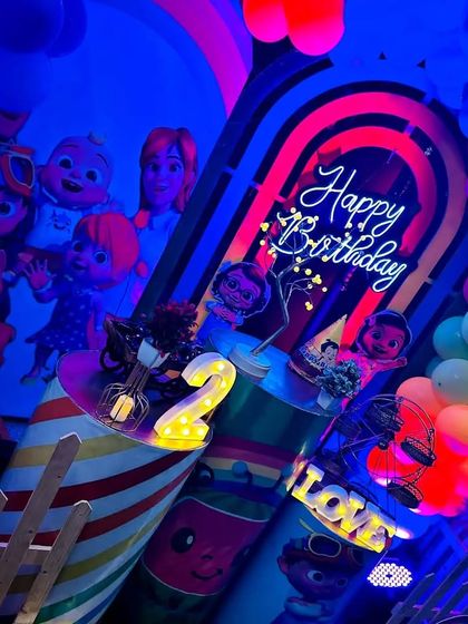 A dynamic, angled shot of the neon-lit Cocomelon birthday party, showing the depth and layers of the decoration.