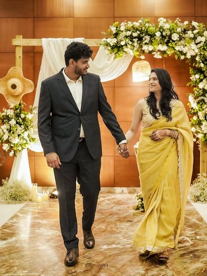 A happy couple walks down the aisle of their rustic-themed engagement. The wooden arch, white florals, and candlelight create a warm and inviting atmosphere.