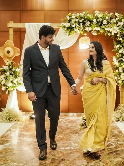 A happy couple walks down the aisle of their rustic-themed engagement. The wooden arch, white florals, and candlelight create a warm and inviting atmosphere.