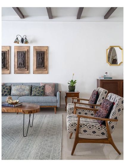 Another angle of the living area, showing the mix of patterned and pastel-colored sofas. The space is framed by storage units, mirrors, and lush plants, creating a layered and inviting atmosphere.