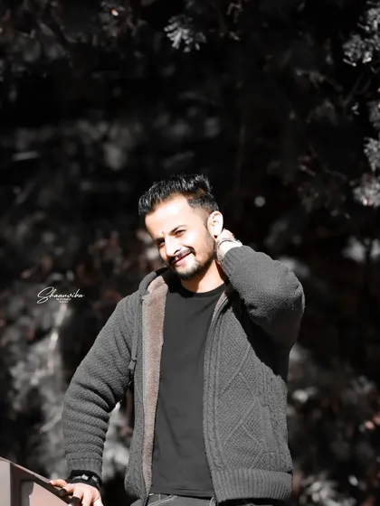 A candid, smiling portrait with a dark, moody background. The contrast makes the subject's expression the main focus of the image.