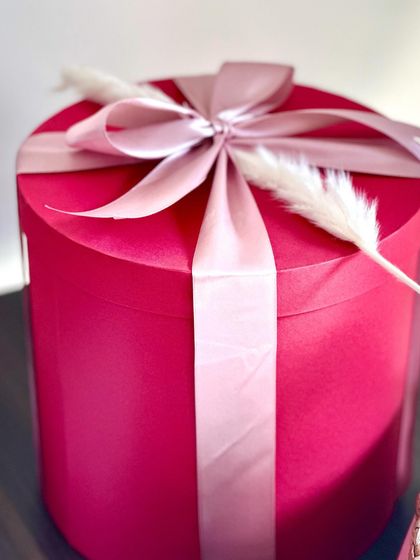 The elegant packaging of our red round box hamper, tied with a beautiful pink satin ribbon.