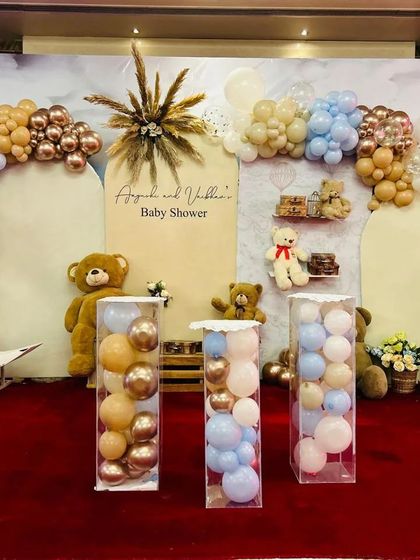 This baby shower backdrop features beautiful arches and a soft color palette of blue, beige, and rose gold balloons. We filled clear acrylic boxes with balloons and added teddy bears to complete this adorable and trendy look.