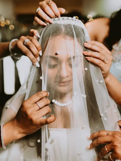 Many hands come together to place the veil on the bride, a beautiful moment of shared participation.
