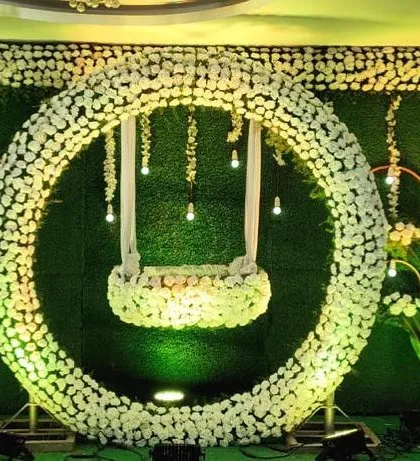 For a grand naming ceremony, we designed this stunning floral ring with a hanging cradle. This modern setup against a lush green wall creates a dramatic and beautiful centerpiece for the event.