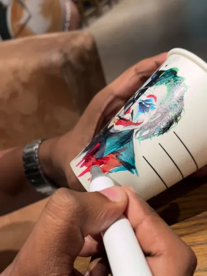 Adding the chaotic colors to the Joker's face on the coffee cup. The splattered, vibrant style contrasts with Batman's clean lines.
