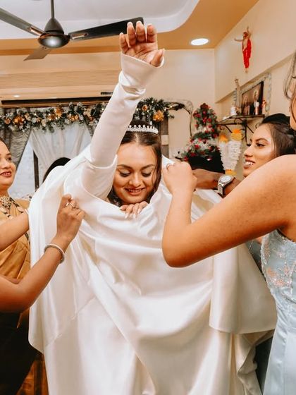 The struggle is real! A fun, candid moment of the bride and her bridesmaids wrangling the wedding dress.