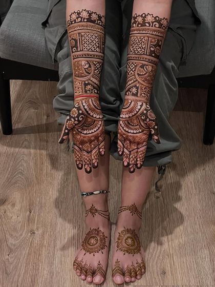 A complete view of a bridal mehendi session, with full-arm designs and matching mandala patterns on the feet.