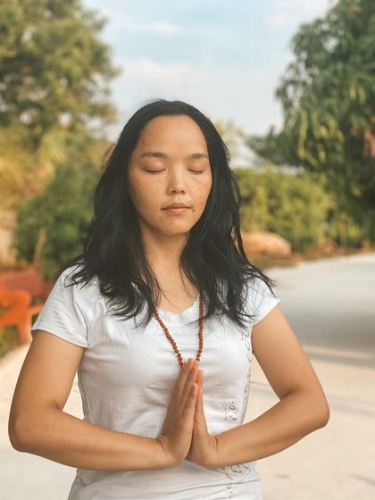 A student stands in prayer, her eyes closed in quiet contemplation. The ashram provides countless opportunities to find moments of peace and connect with your inner self throughout the day.