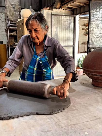 There is no age for learning. This student is rolling out a large slab of dark clay with focus and power, proving that creativity is timeless.