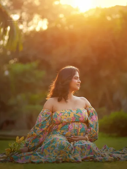 A beautiful solo portrait of the mother-to-be sitting on the grass, bathed in the warm glow of the setting sun. A truly peaceful and radiant moment.