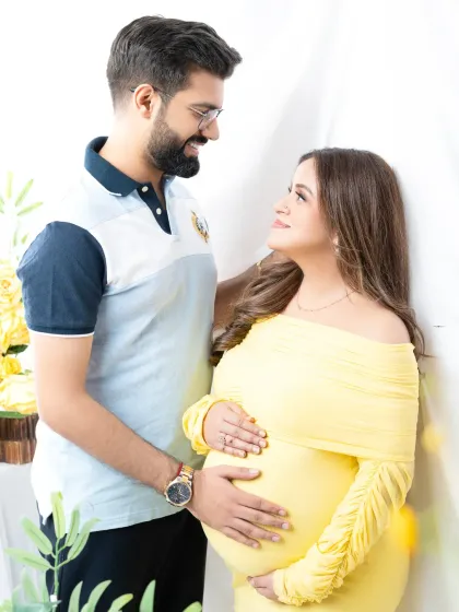 A happy and relaxed couple's portrait. Their bright smiles and the cheerful yellow of the mother's gown create a joyful and sunny atmosphere.