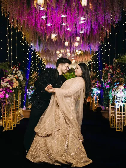 A beautiful dance pose under a canopy of purple flowers and hanging lights. This dynamic portrait captures movement, romance, and the magical ambiance of the wedding reception.
