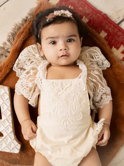 A beautiful overhead shot of the baby in a delicate lace outfit.