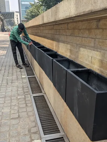 I am making final adjustments to the alignment of the black FRP planters. Attention to detail is what ensures a professional and polished result for our corporate clients.