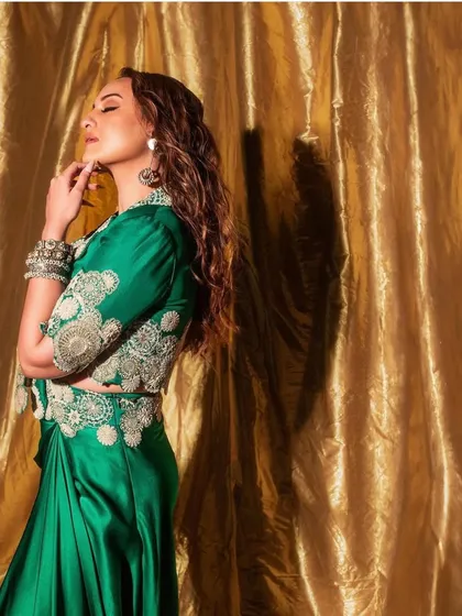 A side profile of Sonakshi Sinha's promotional look for 'Heeramandi', highlighting the detailed craftsmanship of the Anamika Khanna blouse and the elegant drape of the satin skirt.