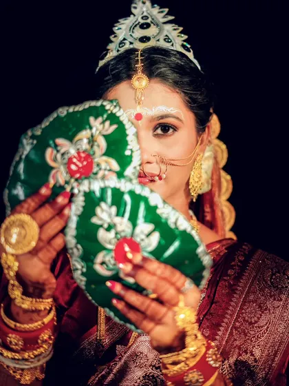 The iconic Shubho Drishti moment from a Bengali wedding. The bride's coy glance from behind the betel leaves is a beautiful tradition that I am always honored to capture.
