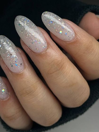 A sheer, iridescent glitter polish over a natural base. This look is subtle yet magical, with glitter that flashes different colors as the light hits it.