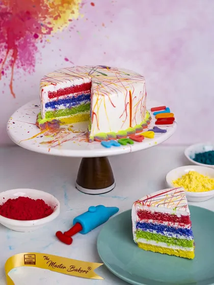 A surprise inside. This Holi-themed cake looks festive on the outside with its colorful splashes, but cutting into it reveals vibrant rainbow layers, making it a true celebration of color.