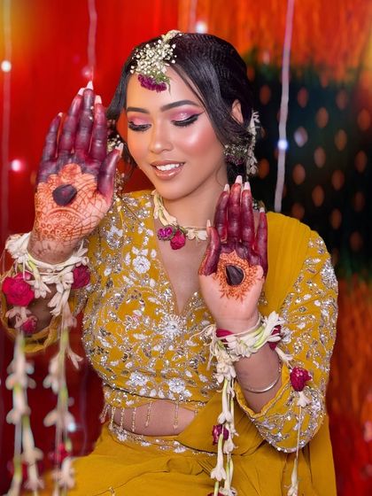 A beautiful Haldi ceremony look. The yellow outfit and floral jewelry are complemented by pink-toned makeup.
