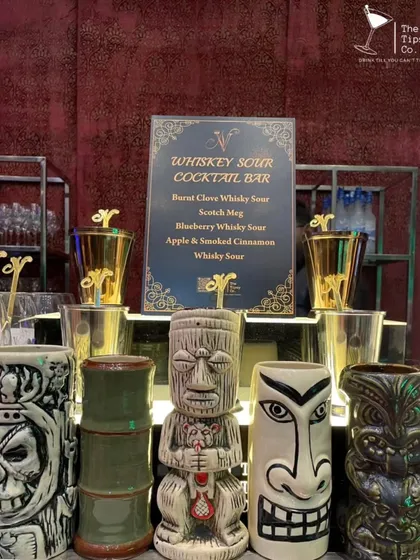 A specialized Whiskey Sour Cocktail Bar. The menu offers creative variations like 'Burnt Clove' and 'Apple & Smoked Cinnamon', served in a variety of unique tiki mugs.