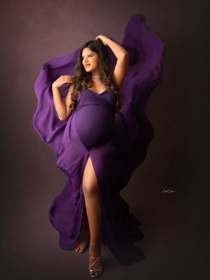 A bold and artistic pose. This mom-to-be lies on the floor, with the vibrant purple fabric of her gown spread out around her like wings.