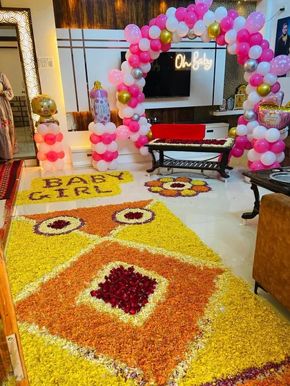 An elaborate flower rangoli and 'BABY GIRL' text made from petals, part of a grand home welcome decoration.
