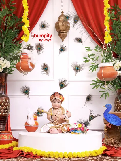 Our little Gopal surrounded by peacock feathers and hanging matkis. The entire set is designed to recreate the divine atmosphere of Vrindavan for your baby's Janmashtami photos.