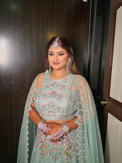 A full view of Riddhi's mehendi look, with makeup that complements her colorful and festive attire.