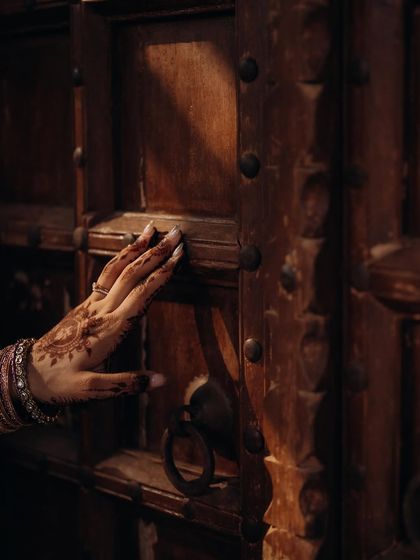 A detailed shot of the bride's hand, adorned with mehndi and bangles, resting on an old wooden door. This tells a story through small, beautiful details.