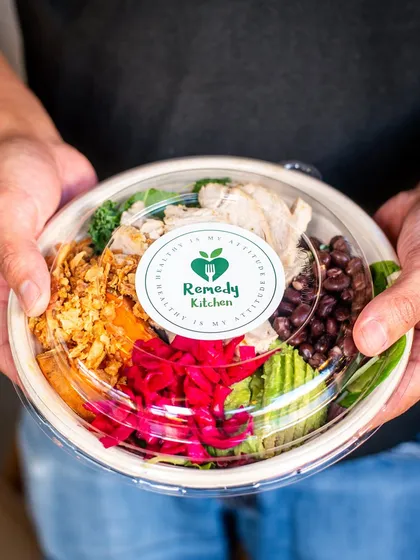 A healthy takeaway bowl held by a customer. This adds a human touch and shows the product in a real-world context.