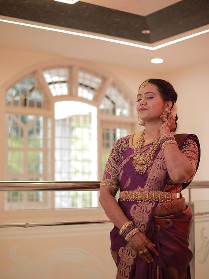 A moment of quiet grace. Madhu's purple saree and traditional gold jewelry are a perfect match.