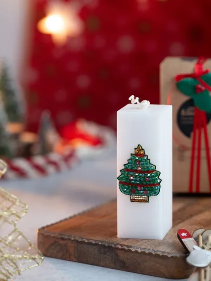 This white pillar candle features a beautifully beaded Christmas tree design. It's an elegant and festive piece.