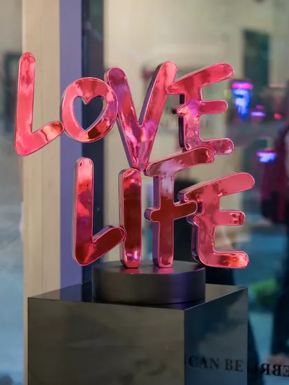 The 'Love Life' sculpture by Pratish Panchal. Rendered in soft pink chrome, this artwork is a simple yet powerful reminder to cherish life's moments, big and small.