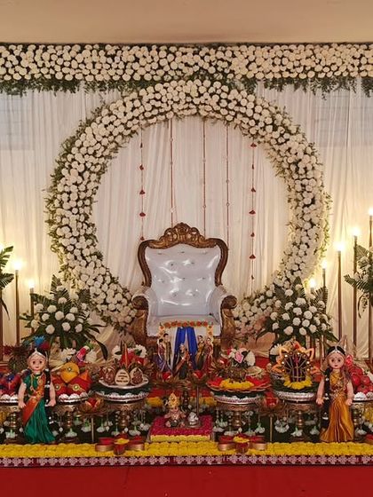 An elegant baby shower setup with a white floral arch and a full display of traditional plates, creating a clean and classic look.